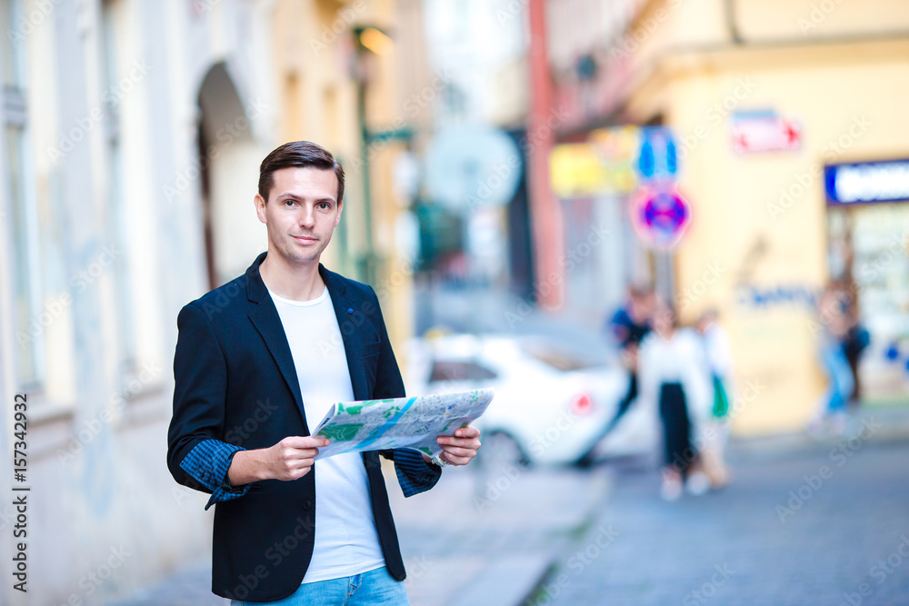 Man tourist with a city map and backpack in Europe street. Caucasian boy looking with map of European city. Man tourist with a city map and backpack in Europe street. Caucasian boy looking with map of European city.