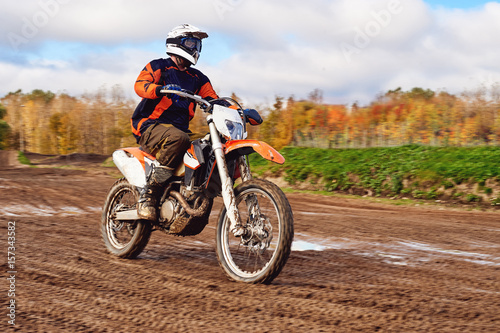 Motocross  enduro rider on dirt track. The forest behind him