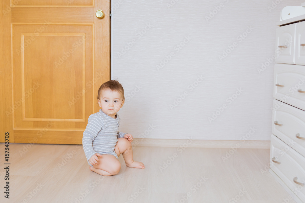 Cute baby boy toddler sitting on the floor in bedroom Cute baby boy toddler sitting on the floor in bedroom