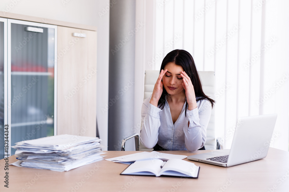 Businesswoman having headache in her office after doing very hard work Businesswoman having headache in her office after doing very hard work