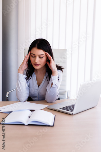 Businesswoman having headache in her office after doing very hard work