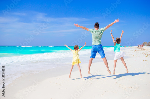 Family of dad and kids walking on white tropical beach on caribbean island have a lot of fun