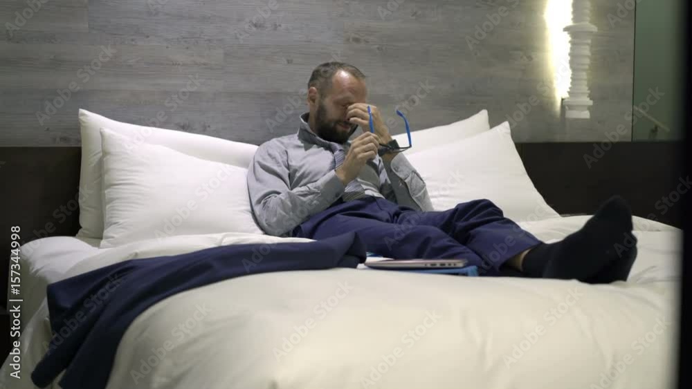 Tired businessman having headache lying on bed in hotel room at night
Tired businessman having headache lying on bed in hotel room at night