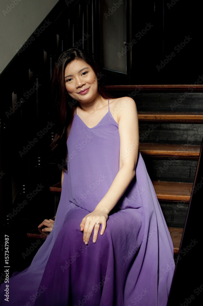 A pregnant woman wearing a purple dress indoors