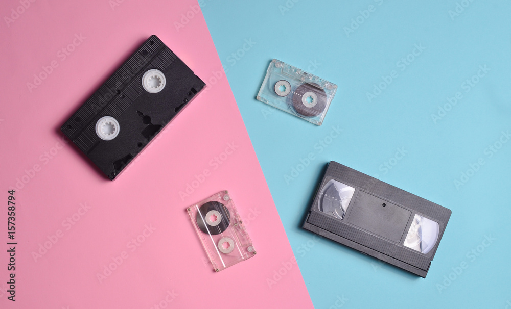Audio cassettes and video cassettes are laid out on a multi-colored neon surface. Top view.
Audio cassettes and video cassettes are laid out on a multi-colored neon surface. Top view.