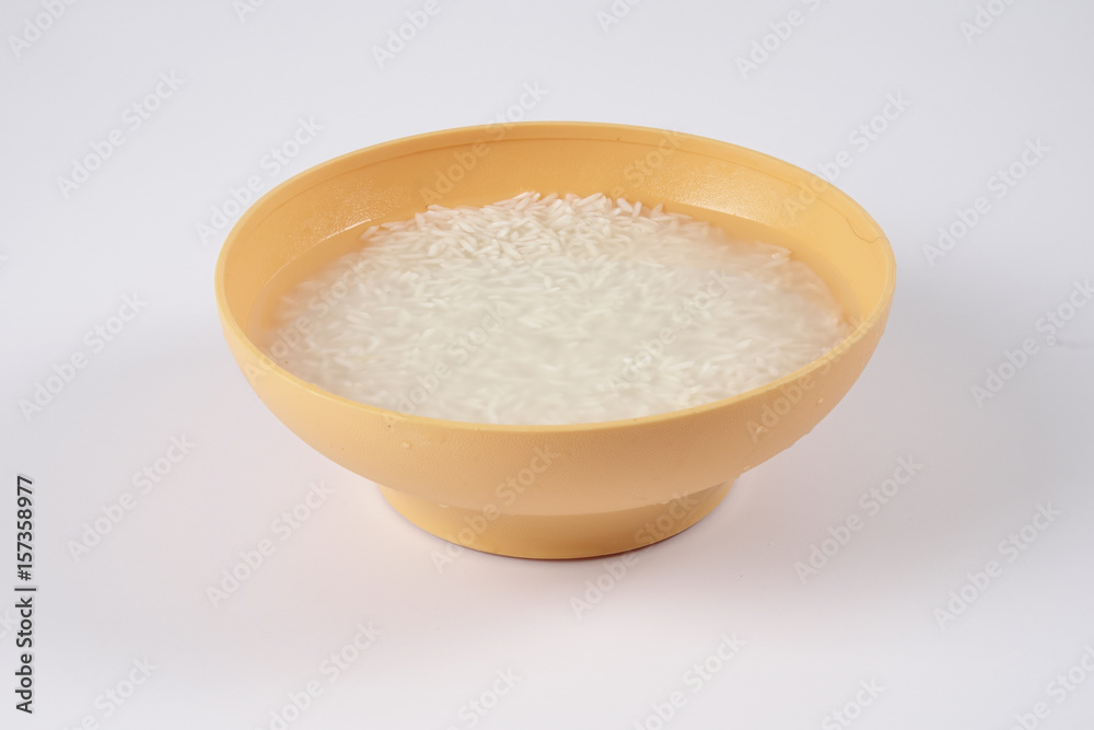 Soak rice in yellow bowl over white background Soak rice in yellow bowl over white background