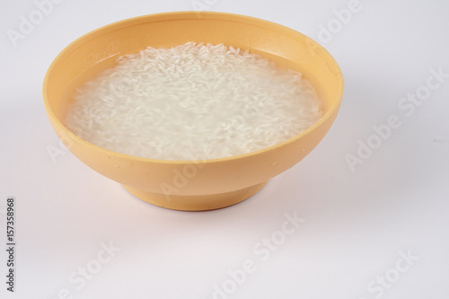 Soak rice in yellow bowl over white background