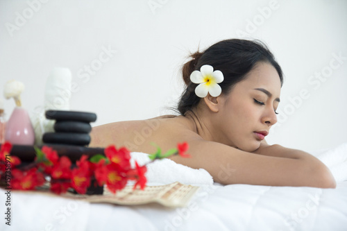 Beautiful girl lay down on spa bed. Young woman in spa shop. Asian girl lay down on bed in spa with hot stone on back. Happy lifestyle concept.