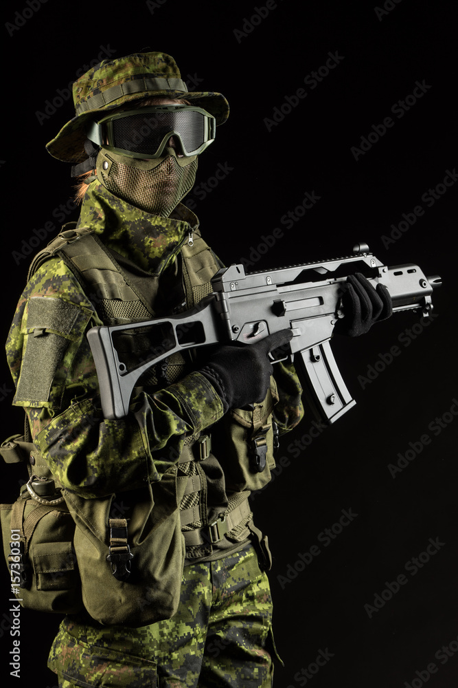 Portrait of armed woman with camouflage. Young female airsoft sniper observe with firearm. Soldier with gun in war, black background.  Military, army people concept