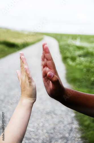 White girl and ethnic girl giving each other high fives, while they are walking on  on the road i Europe © bettysphotos