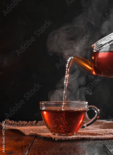 Process brewing tea,tea ceremony,Cup of freshly brewed black tea,warm soft light, darker background.