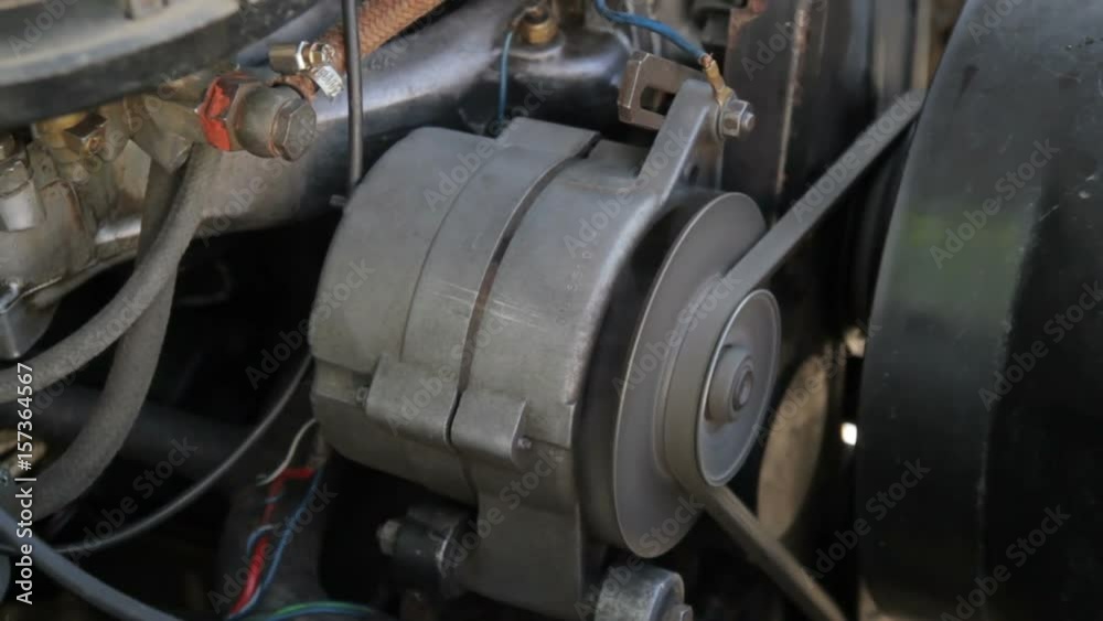 Old mechanic repairing an old car. Under the hood of the car checks the work of carb and engine Old mechanic repairing an old car. Under the hood of the car checks the work of carb and engine