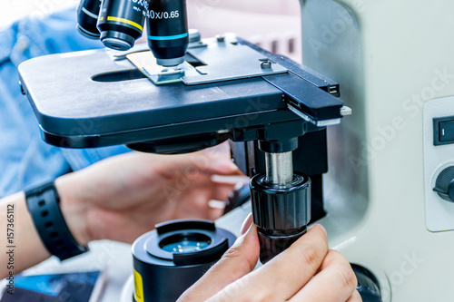 Close up view of scientist hands with a slide ofthe sample in the microscope for research in laboratory.. photo