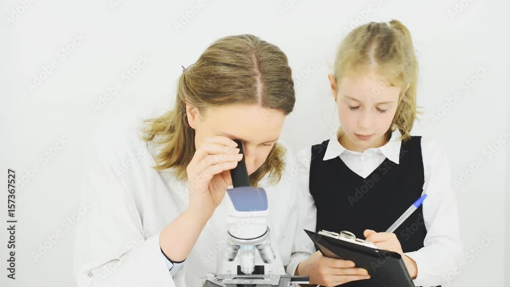 Woman and little girl using microscope in laboratory. Woman and little girl using microscope in laboratory.