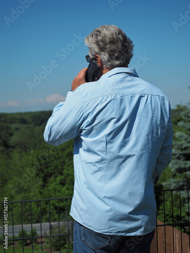 Senior man with mobile phone in garden.