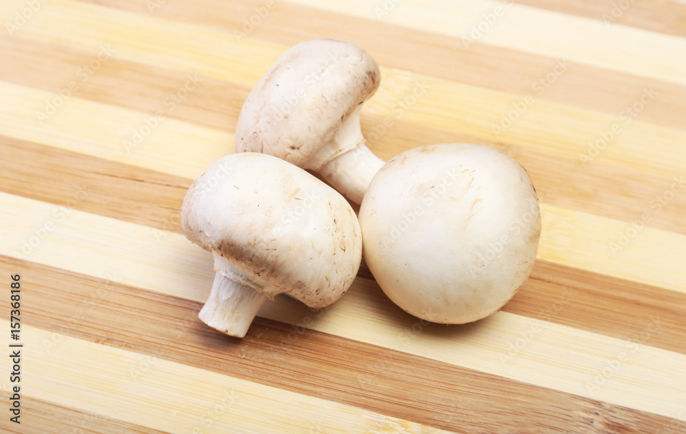 Fresh white mushrooms champignon on wooden background.