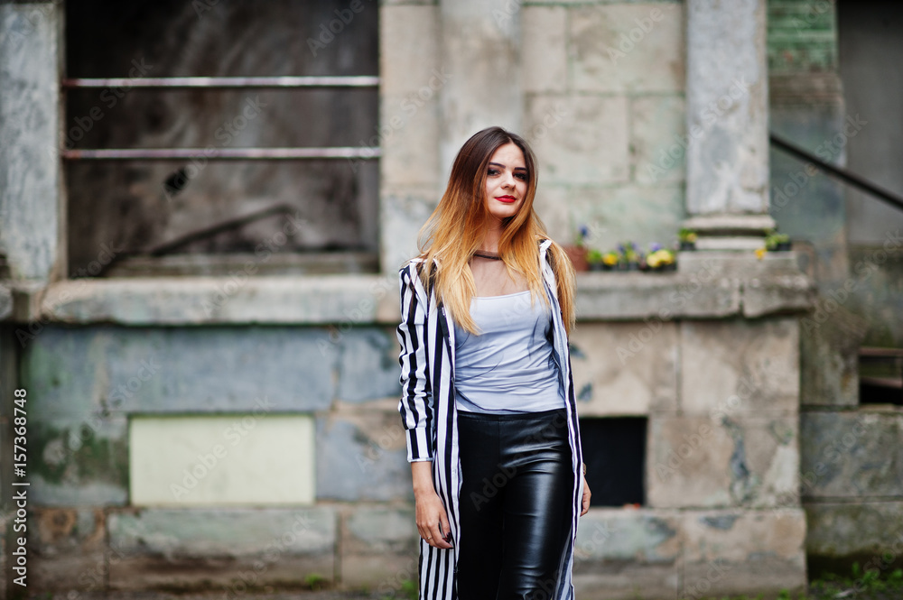 Fashionable woman look with black and white striped suit jacket, leather pants, posing at old street. Concept of fashion girl. Fashionable woman look with black and white striped suit jacket, leather pants, posing at old street. Concept of fashion girl.