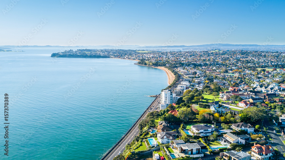 Obraz premium Aerial view on a road running along sea shore with residential suburbs on the background. Auckland, New Zealand.