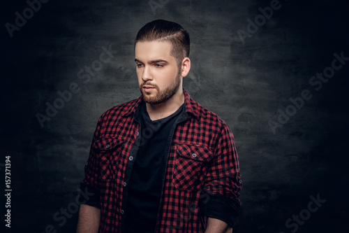 Bearded hipster male dressed in a red fleece shirt over grey background.