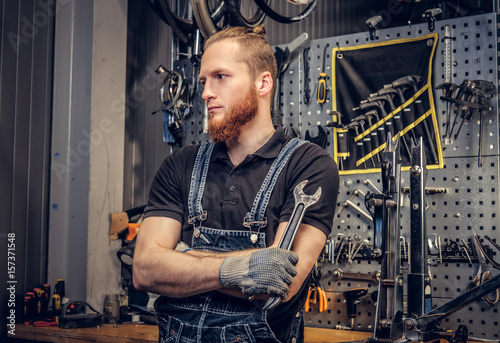 Biicycle mechanic with crossed arms holds cup key over. © Fxquadro