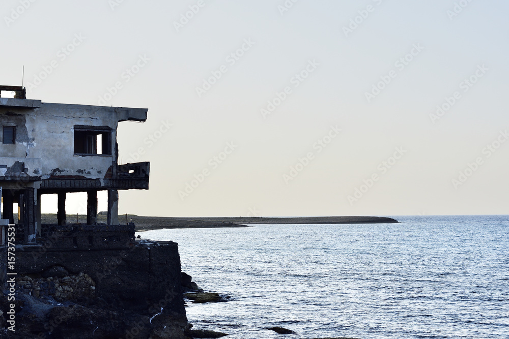 Ruin house close to the sea with blue water and blue sky