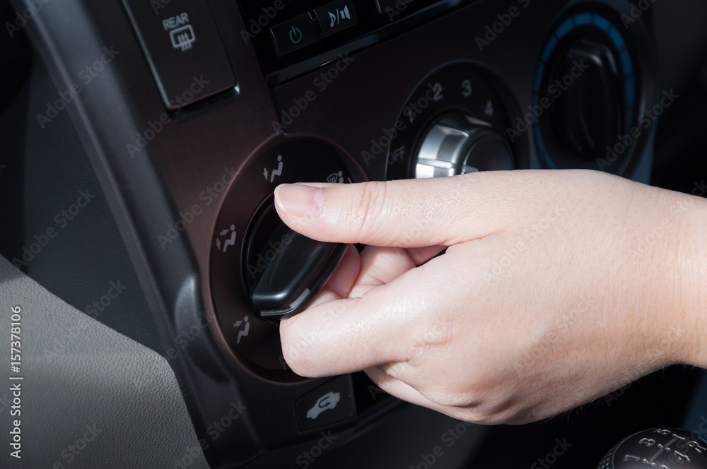 Woman hand turning on car air conditioning system