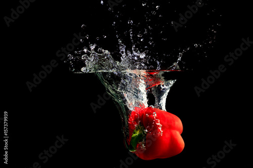 Red pepper splashing water on black background
