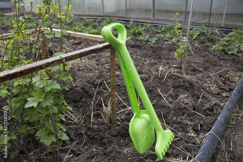 Children's rake and shovel in the garden leaning against the fence in the spring photo