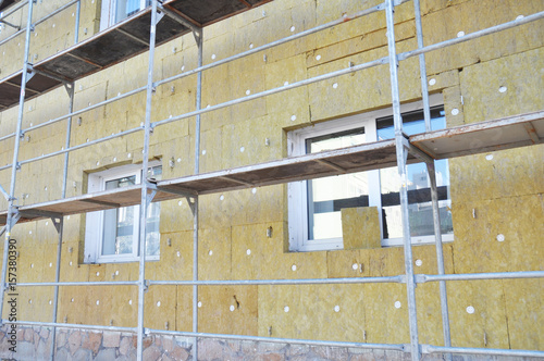Install Rock Mineral Wool Insulation. Energy efficiency house wall  renovation for energy saving. Exterior house wall heat insulation with mineral wool, building under construction.