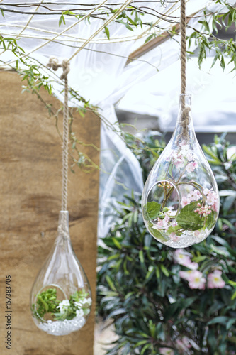 Original ornaments of small glass vases hanging with pink flowers