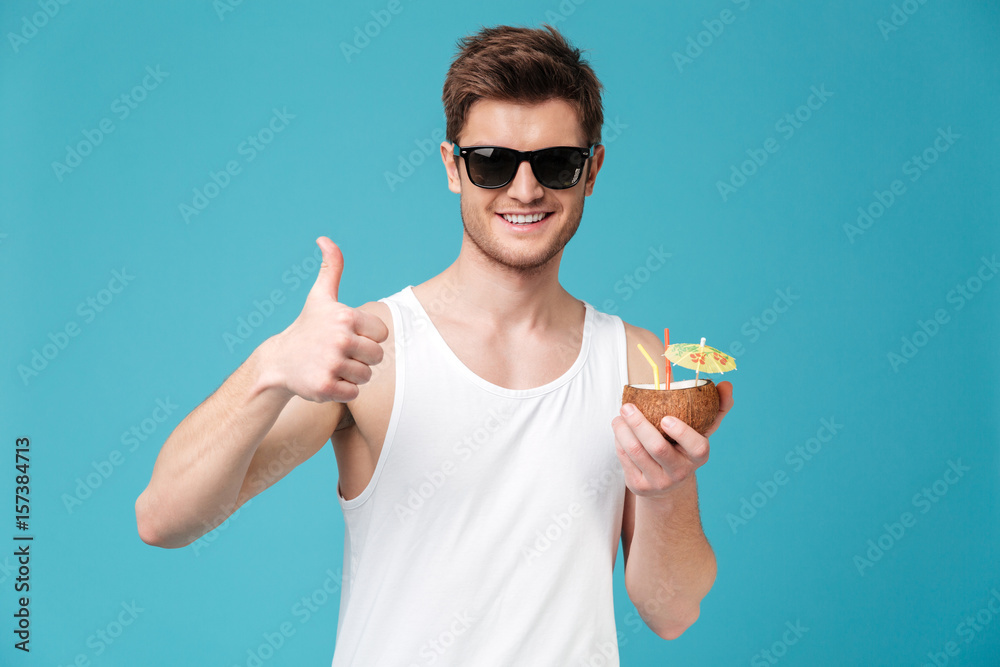 Happy man drinking cocktail and showing thumbs up.