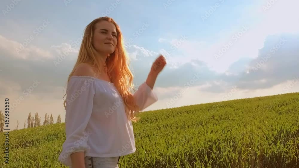 Happy woman with long hair walks on summer green field at sunset slow motion Happy woman with long hair walks on summer green field at sunset slow motion