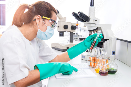 Women Scientist checking test sample with microscope photo