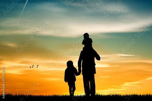 father with sons silhouette at sunset