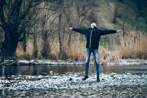 Happy jumping man in beautiful river landscape