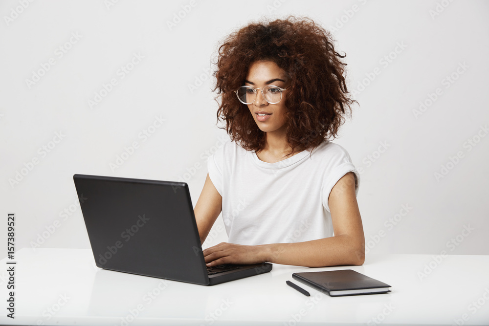 African business lady smiling working at laptop over white background. African business lady smiling working at laptop over white background.