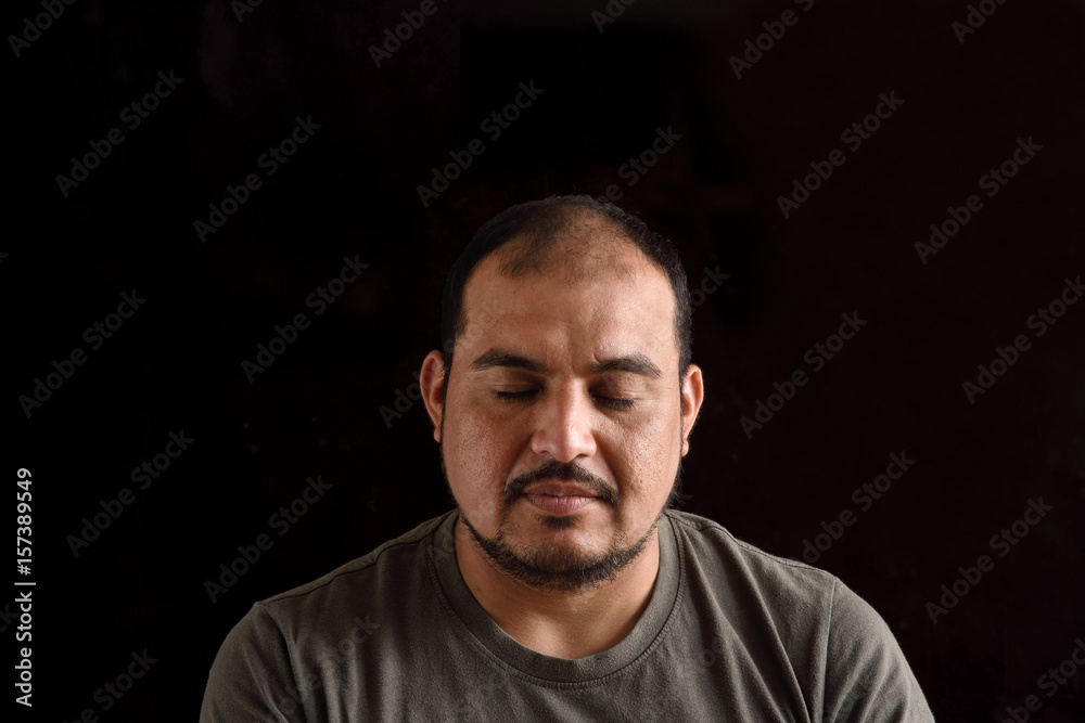 Portrait of a latin man with eyes closed with black background
