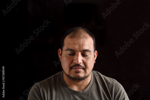 Portrait of a latin man with eyes closed with black background