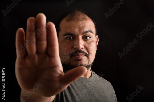 Portrait of a latin man with stop sing on black © curto