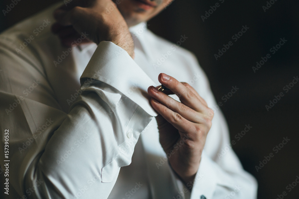 The groom wears  cufflinks for shirt  in the room