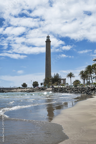 Vertical shot of large, beautiful beach, on a partially cloudy day, in front of Faro de Maspalomas or Maspalomas lighthouse, Gran Canaria, Spain