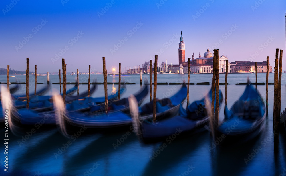 Venice sunset with motion blur effects on Gondola. Amazing blue and purple sky