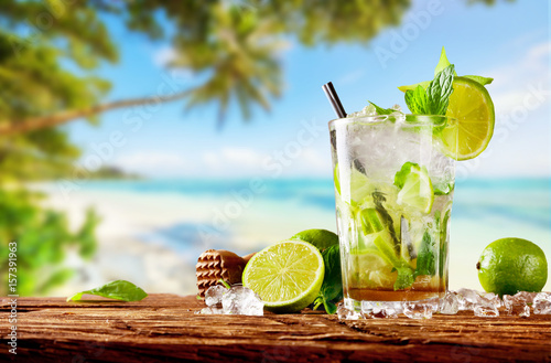 Fresh mojito drink placed on wooden planks, blur beach on background