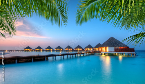 Canvas-taulu Water villas on Maldives resort island in sunset