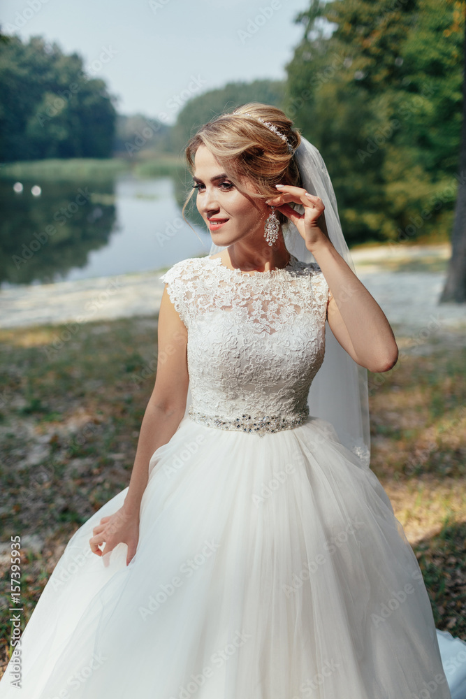 Gorgeous bride holds her hand before beautiful face standing on the lake shore Gorgeous bride holds her hand before beautiful face standing on the lake shore
