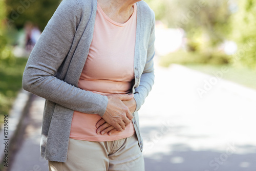 Upset old woman having sudden pain in the stomach outdoors