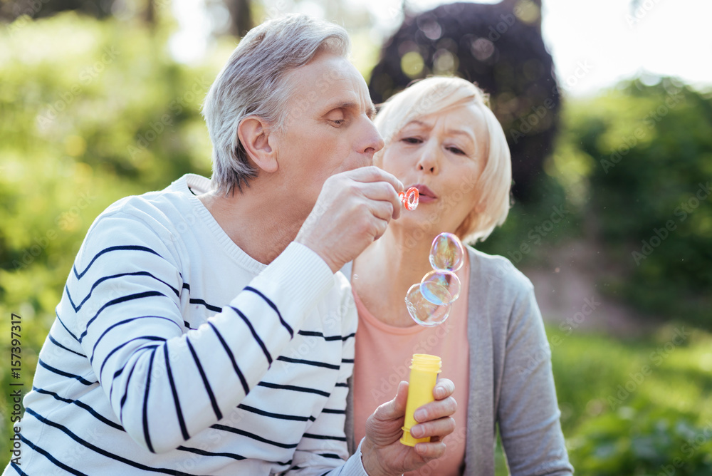 Delighted pensioners making soap bubbles in the park Delighted pensioners making soap bubbles in the park