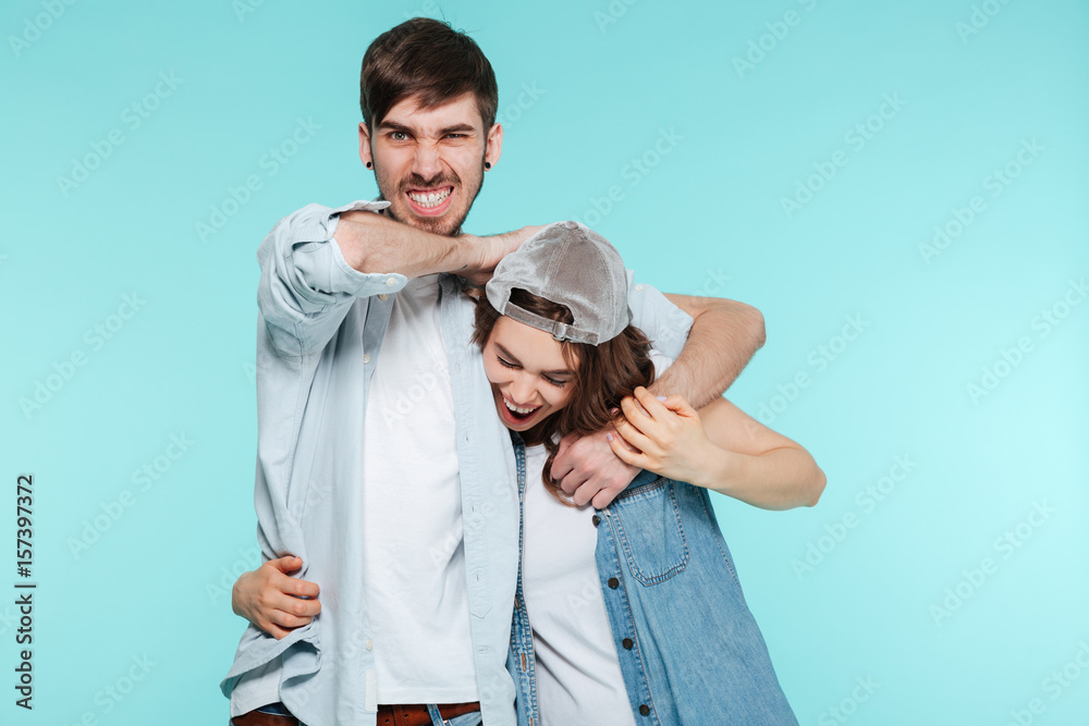 Fototapeta premium Joyful man playing and torturing his displeased young sister