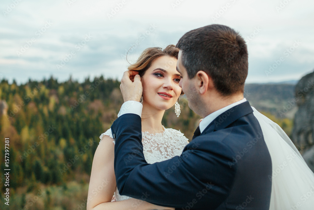 Lovely wedding couple stands among the rocks before a golden forest