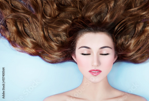 Wallpaper Mural Beautiful woman with long brunette hair laying down on the floor. Isolated on light blue background.  Torontodigital.ca
